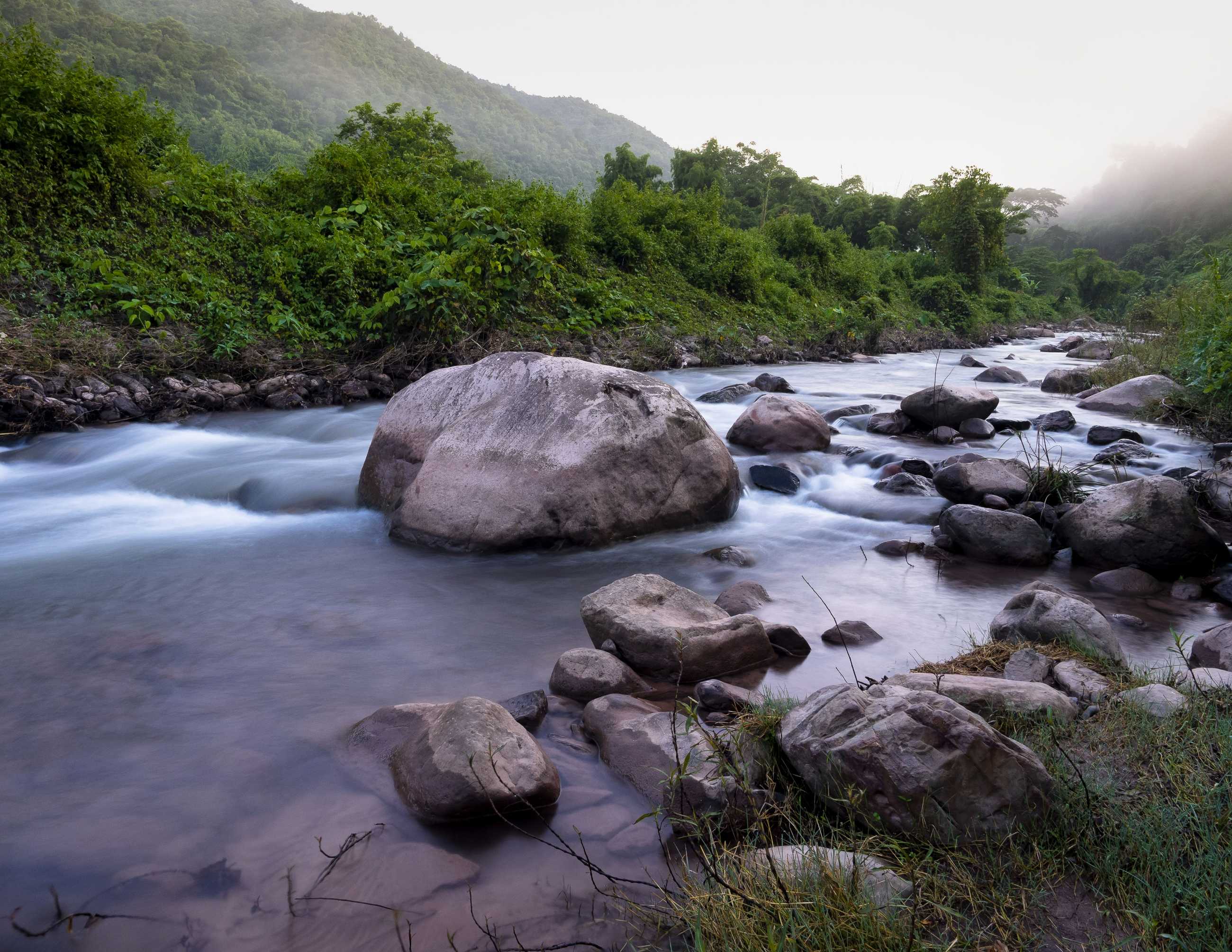 stones-soft-flowing-water-river-fresh-green-forest-mountain-with-fog-natural-lan.jpg